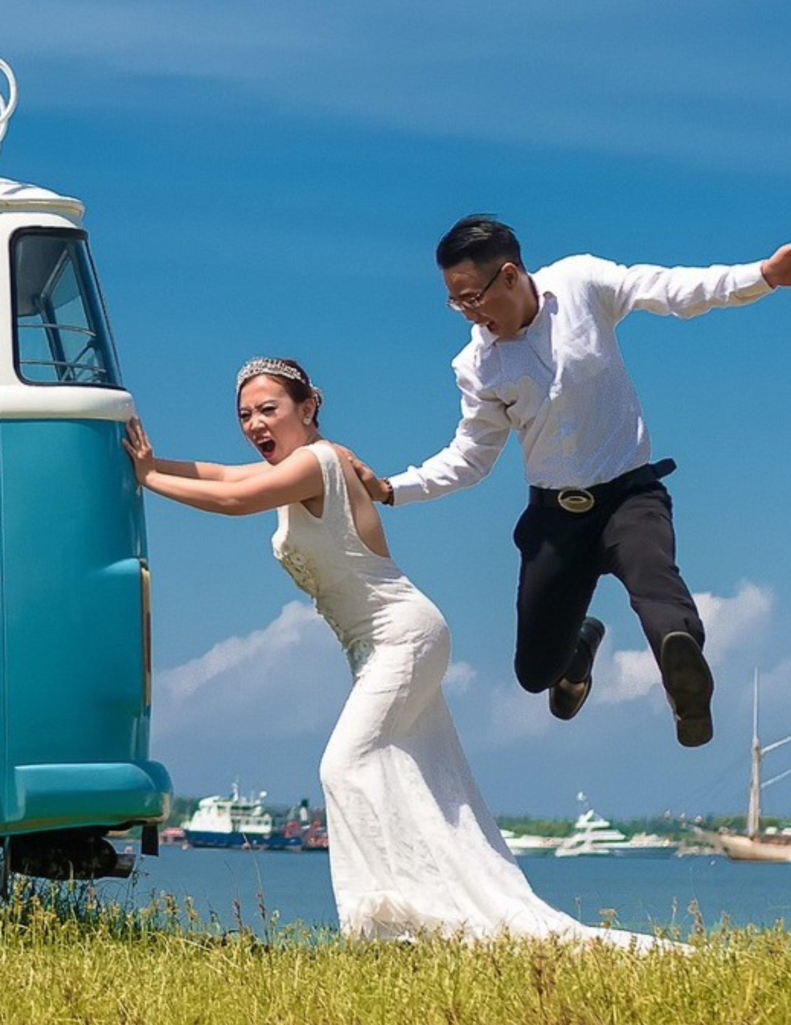 Bride pushing a van while the groom leaps behind her